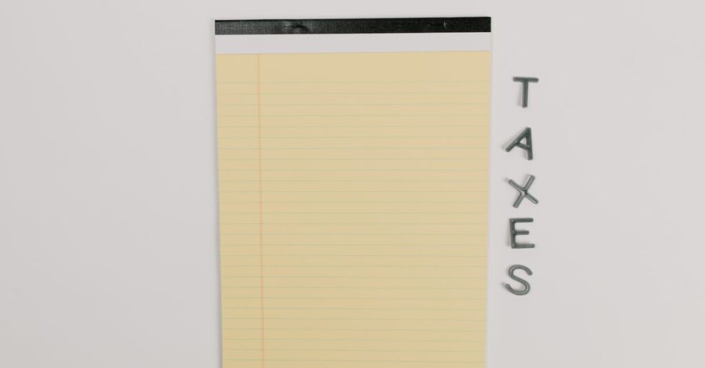Close-up of a yellow legal pad and the word 'TAXES' on a white surface, ideal for finance themes.