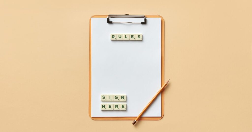 Flat lay of clipboard with letter tiles spelling 'rules' and 'sign here', accompanied by pencil on beige background.