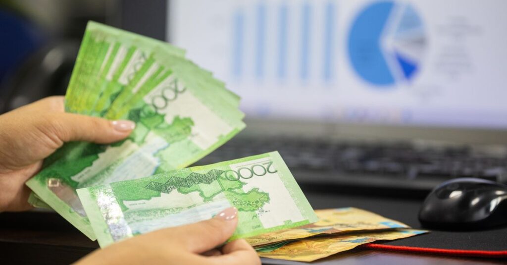 Hands counting cash with financial charts in background, indicating business or finance theme.