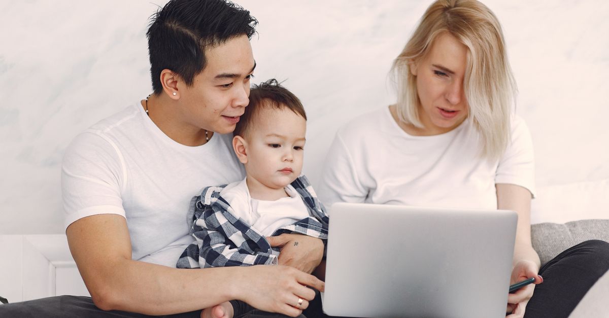 Young family enjoying quality time together, engaging with a laptop indoors.