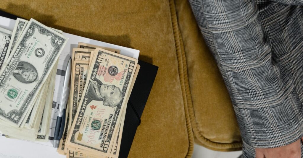 A close-up shot of US dollars on a couch, next to a plaid suit sleeve. Ideal for finance-related themes.