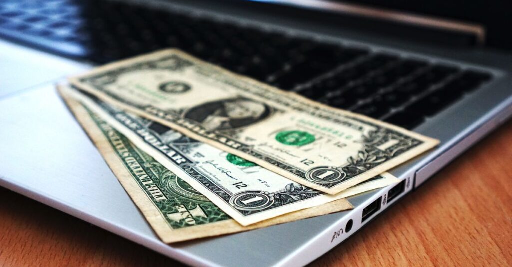 Close-up of US dollar bills placed on a laptop symbolizing digital finance and economy.