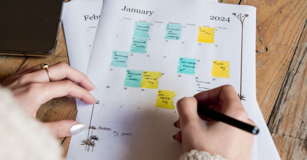 A woman marking events on a January 2024 calendar with colorful notes, focusing on planning.