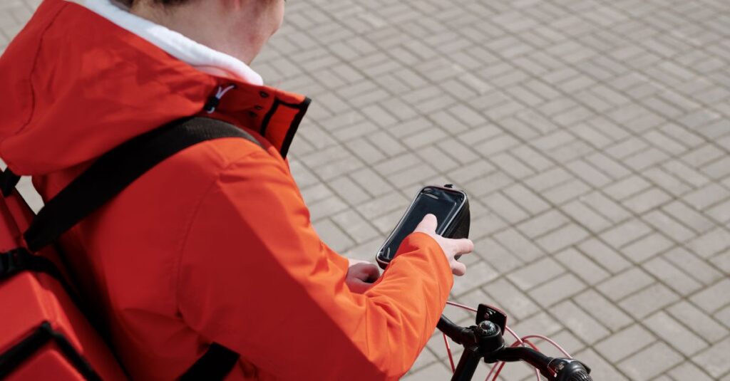 Delivery man on a bicycle checking smartphone for directions.