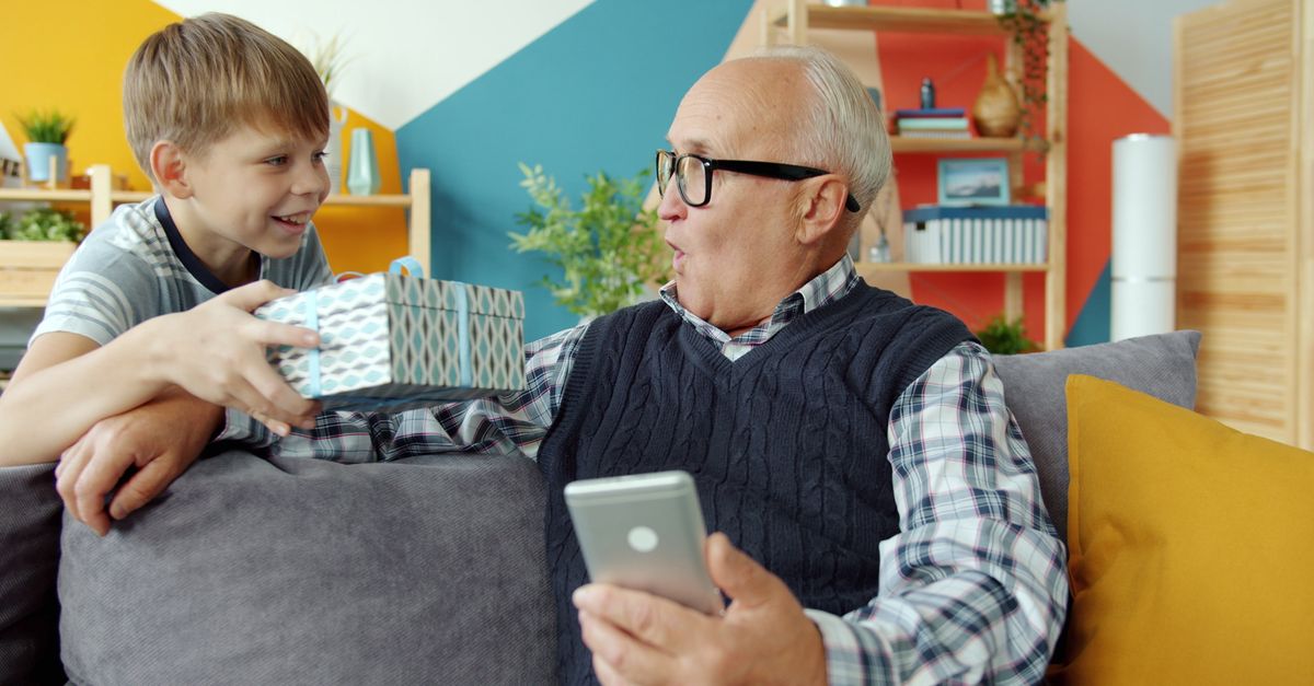 Senior man and boy enjoying a heartwarming gift exchange indoors.