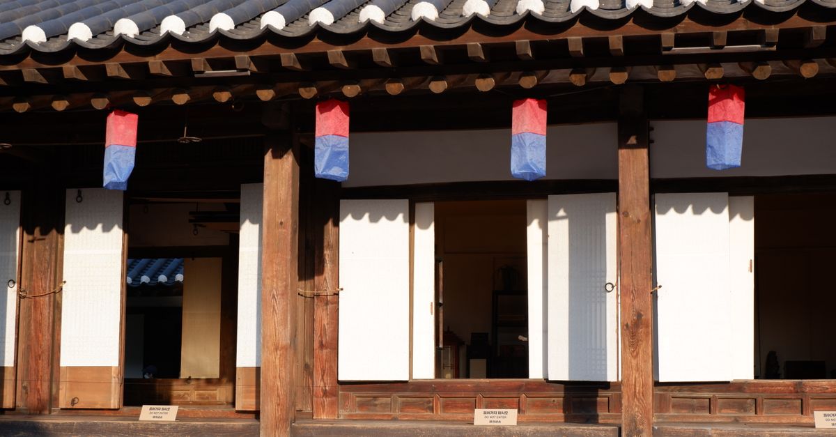 A scenic view of a traditional Korean Hanok with vibrant red and blue lanterns.