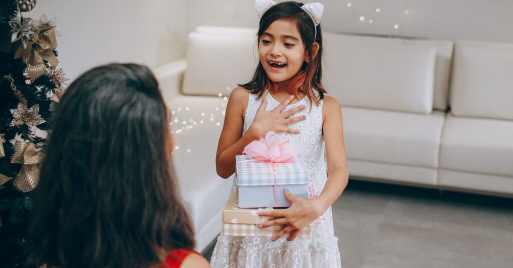A joyful young girl receives a Christmas gift from her mother in a warmly decorated living room.