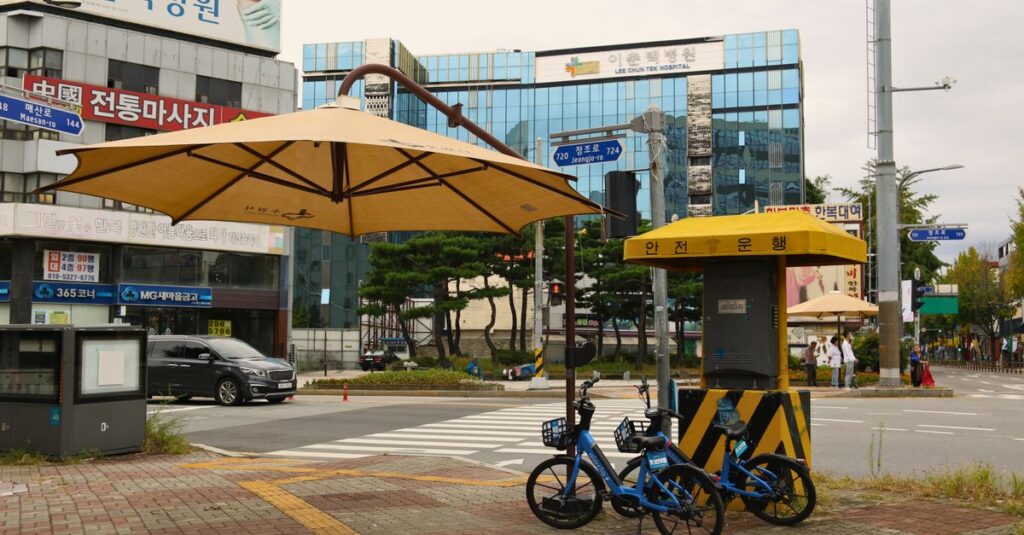 Outdoor scene featuring bicycles and a crosswalk in Suwon, South Korea.