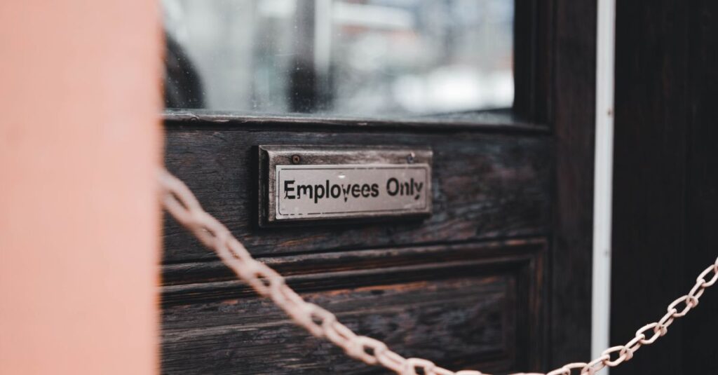 Close-up of an 'Employees Only' sign on a rustic wooden door secured by a chain.