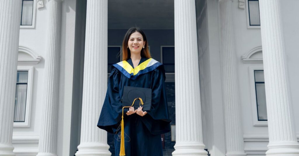 Young woman in graduation attire standing outside a classical academic building, symbolizing success.
