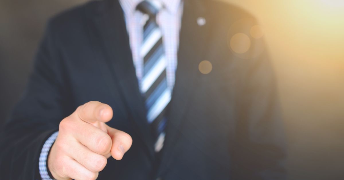Confident businessman in a suit pointing forward, signifying leadership and focus.