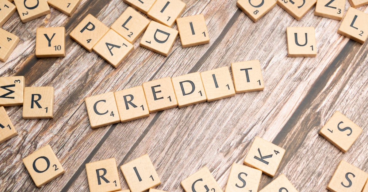Wooden letter tiles arranged to spell 'CREDIT' on a rustic table background.