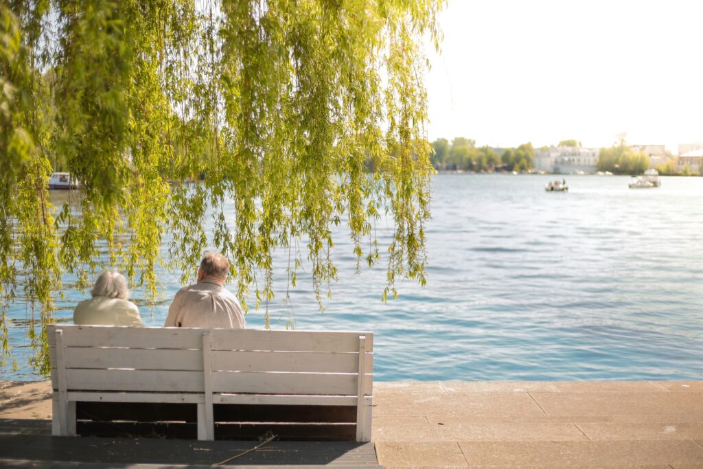 Elderly couple sitting on bench by lake
