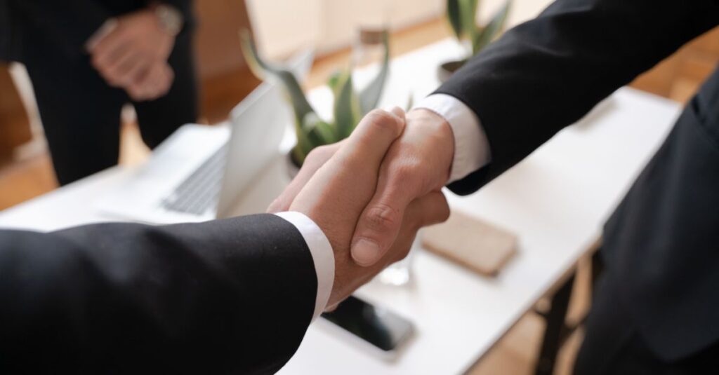 Close-up of a handshake between two professionals in a business setting, symbolizing agreement.