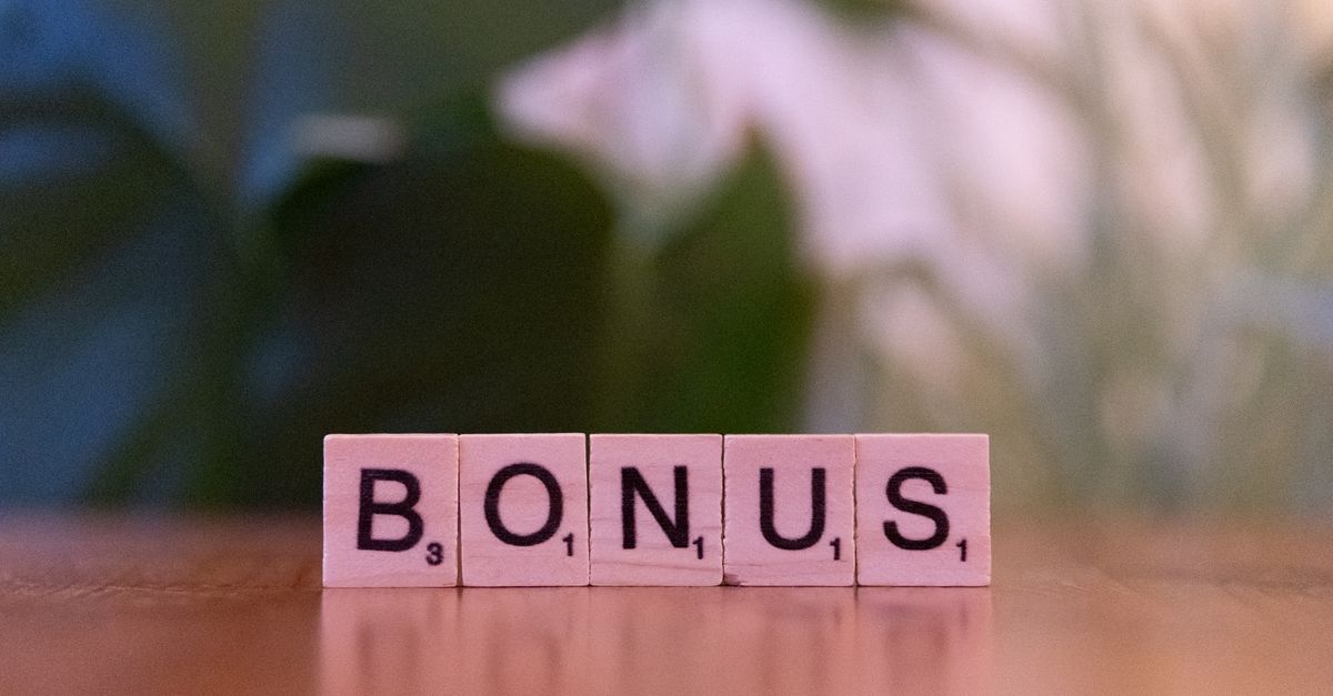 Close-up of the word BONUS spelled with Scrabble tiles on a table.