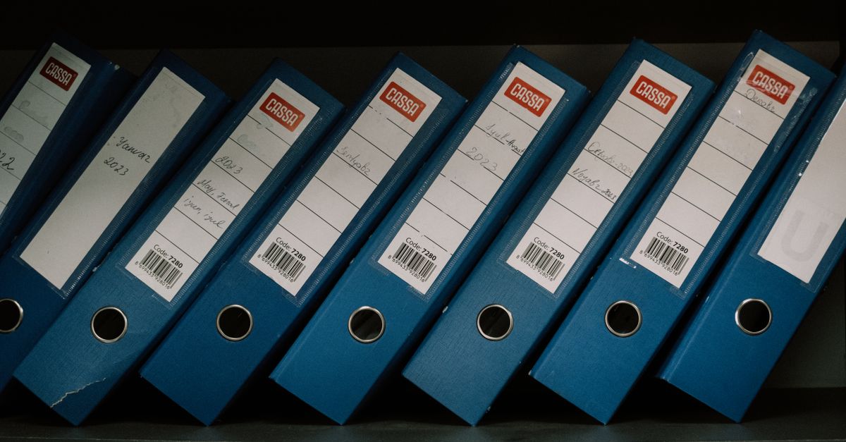 Neatly arranged blue office binders labeled with dates and names for organized storage.