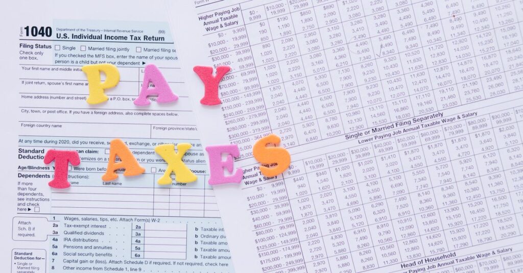 Close-up of U.S. tax forms with colorful 'PAY TAXES' letters emphasizing financial deadlines.