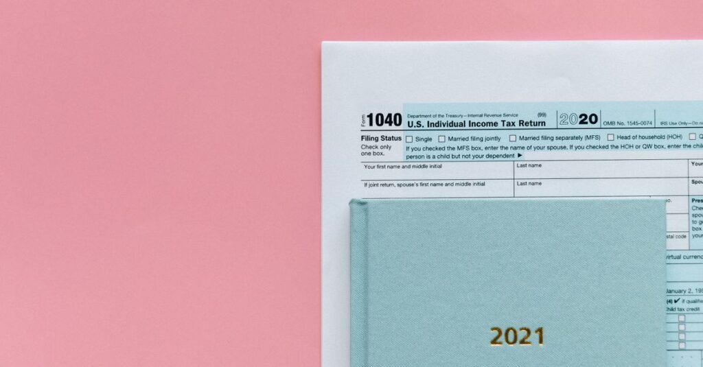U.S. 1040 tax form with 2021 planner on a pastel pink background, symbolizing tax season.