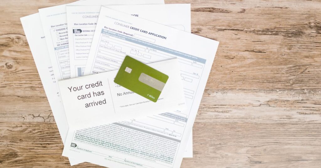 Top view of credit card and application documents on wooden surface.