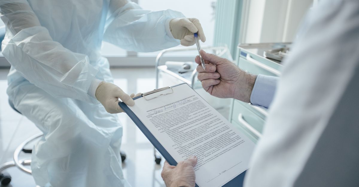 A doctor hands a clipboard to a patient for signature, highlighting medical professionalism.