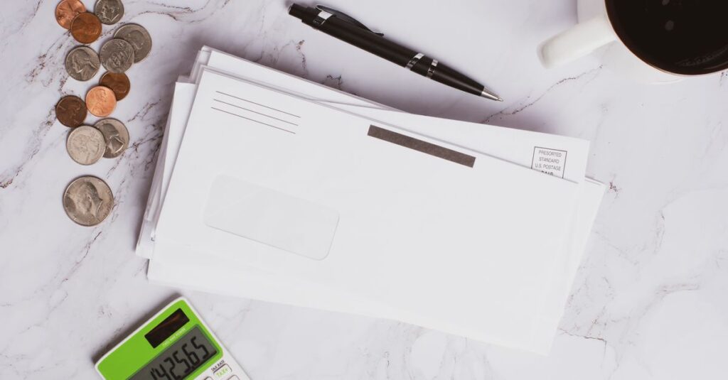 Flat lay of financial documents, calculator, coins, and coffee cup on marble surface.
