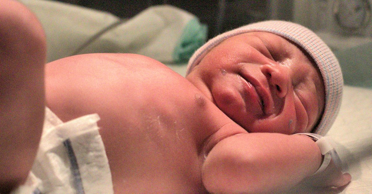 A newborn baby resting peacefully on the hospital bed shortly after birth.