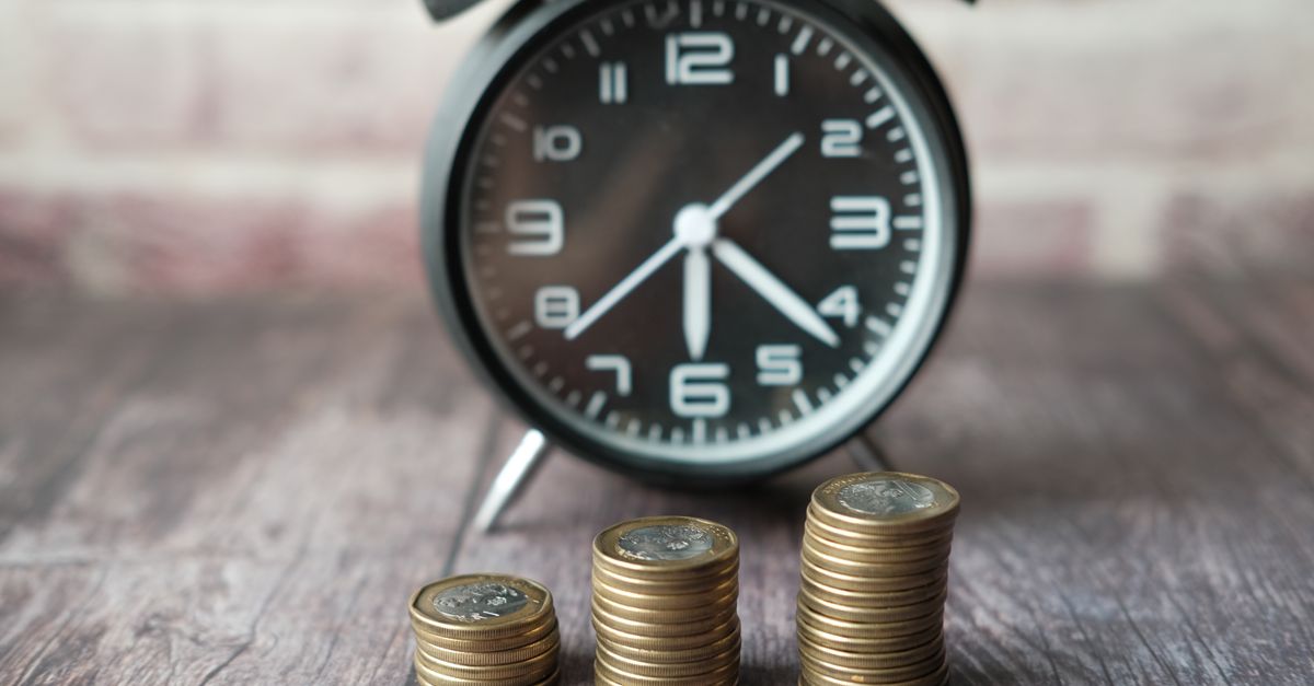 Stacked coins and a classic alarm clock symbolize the value of time and money.