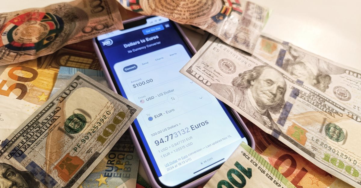 A smartphone displaying a currency converter surrounded by dollar and euro banknotes, highlighting exchange rates.